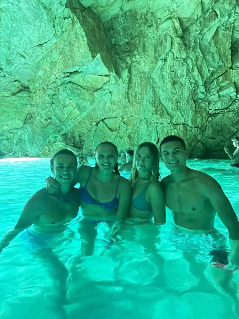 A group of people, inside the hidden cave located in Vlore. The water look blue due to the reflection of the sun entering the cave.