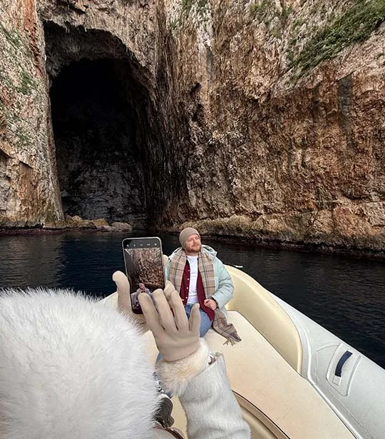A couple taking photo in front of Haxhi Ali Cave entrance, during a boat trip